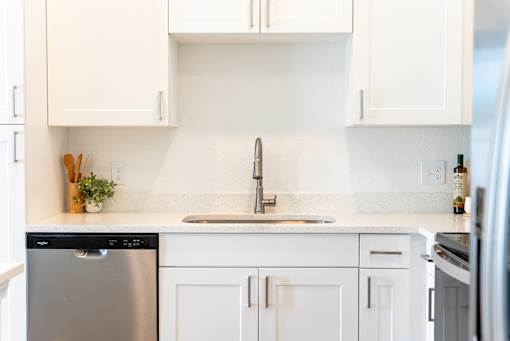 A kitchen with white cabinets and a stainless steel dishwasher.
