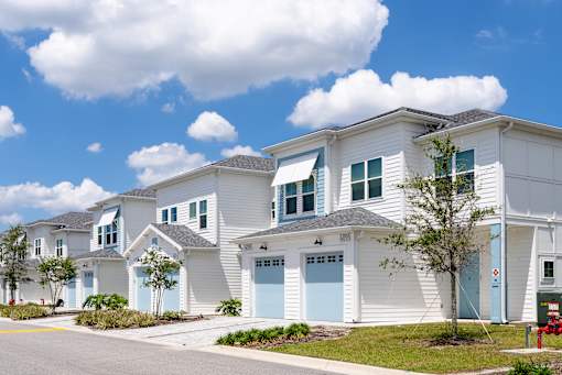 A row of white houses with blue garage doors.