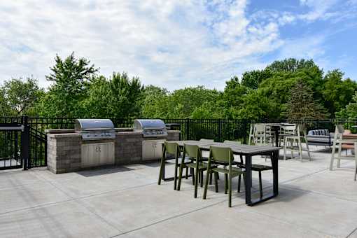 A patio with tables and chairs and a grill.