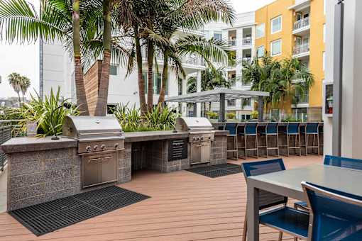 A patio with a grill and chairs.