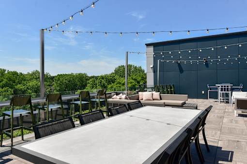 A large table is surrounded by chairs on a patio.