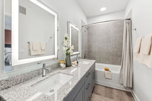 a white and gray bathroom with two sinks and a shower