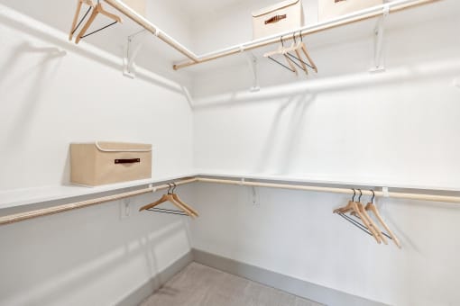 a walk in closet with hangers and a box on the wall