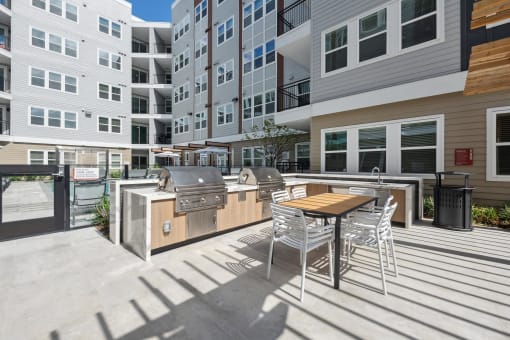 a patio with a table and chairs in front of an apartment building