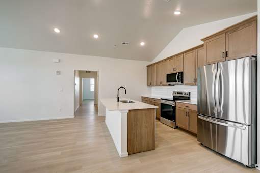 A kitchen with a refrigerator, sink, and oven.