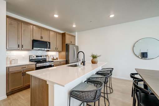 A kitchen with a white countertop and black chairs.