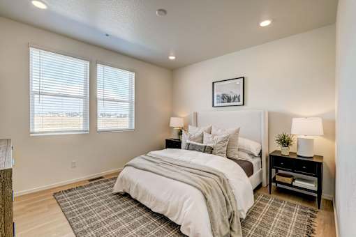 A bedroom with a large bed and a window with blinds.