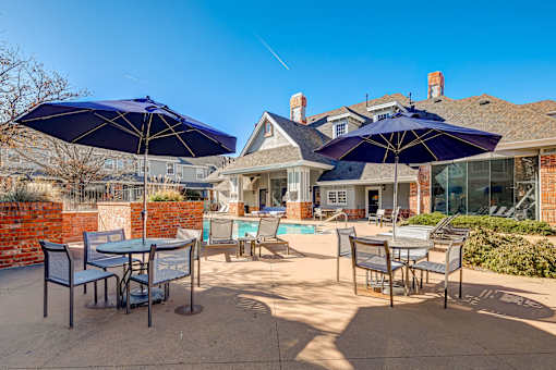 Patio with blue umbrellas at The Retreat at Fox Hollow apartments for rent in Lakewood, CO.