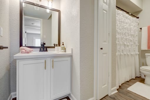 a bathroom with white cabinets and a white shower curtain