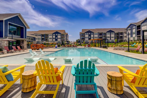 a swimming pool with yellow and blue chairs next to a building