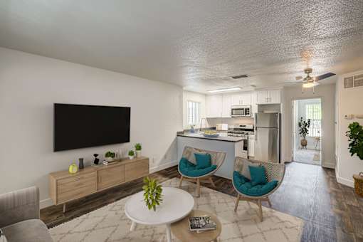 A living room with a television, two chairs, a table, and a plant.
