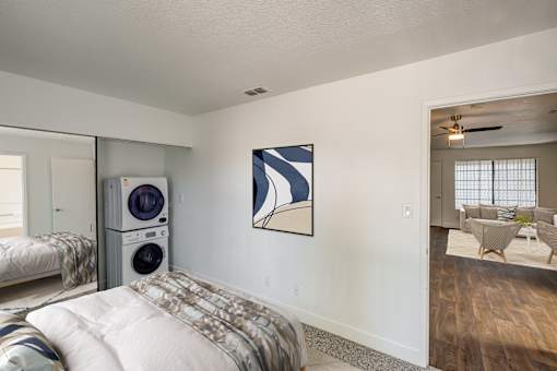 A bedroom with a washer and dryer stacked on top of each other.