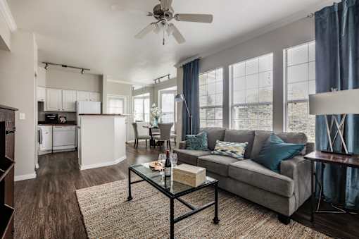 A living room with a grey couch and a glass coffee table.