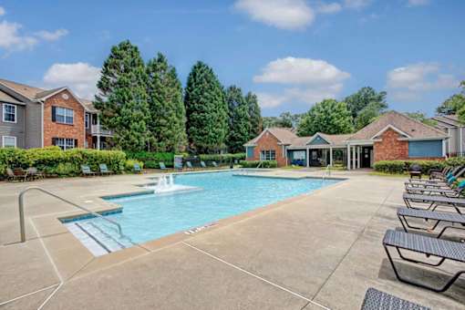 A swimming pool surrounded by lounge chairs and trees.
