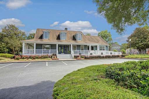 A large house with a porch and a driveway in front.