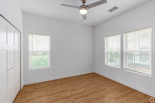 an empty living room with wood floors and a ceiling fan