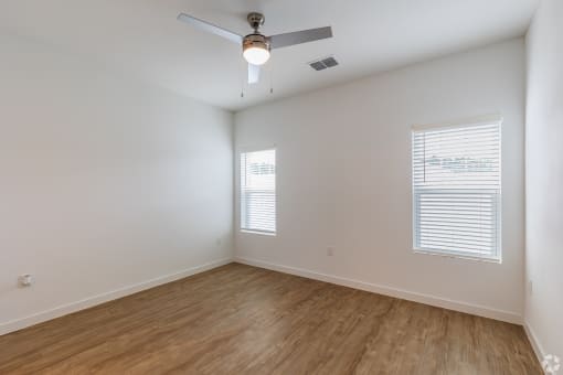 an empty room with hardwood floors and a ceiling fan
