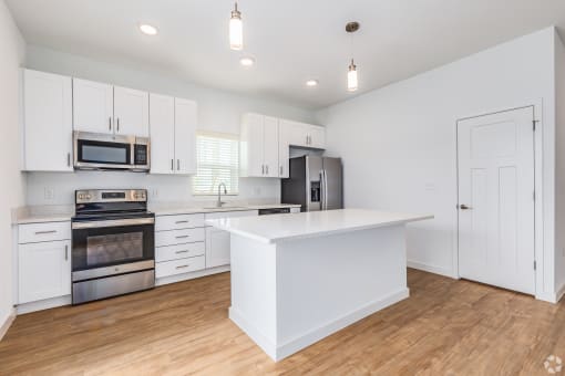 a large kitchen with white cabinets and stainless steel appliances