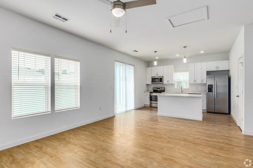 an empty living room and kitchen with white walls and wood floors
