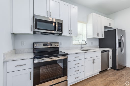 a kitchen with white cabinets and black appliances and a stainless steel refrigerator