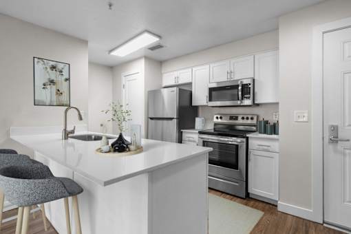 A modern kitchen with white cabinets and stainless steel appliances.