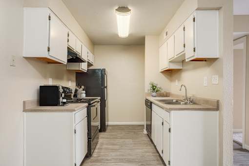 A kitchen with white cabinets and a black refrigerator.