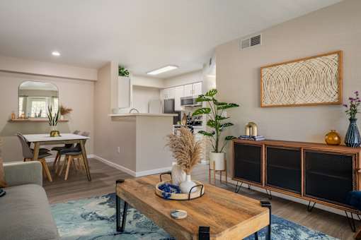 A modern living room with a grey sofa, wooden coffee table, and a large abstract art piece on the wall.