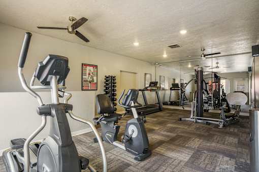 A spacious gym with a variety of equipment including treadmills, stationary bikes, and weight machines.