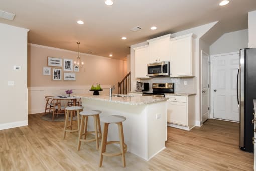 a kitchen with white cabinets and a white counter top with three stools in front of it