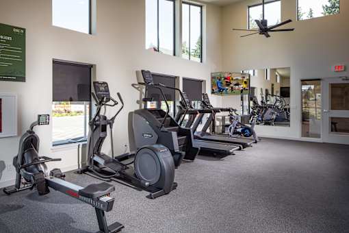 A gym with a variety of exercise equipment including treadmills, elliptical machines, and a rowing machine.