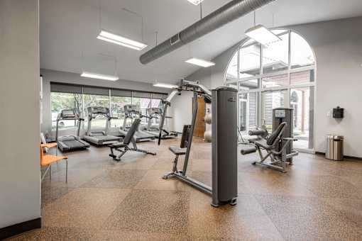 A gym with a variety of equipment including treadmills, weights, and exercise machines.