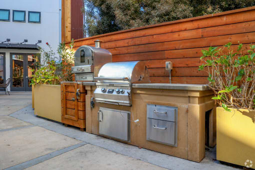 a stainless steel barbecue grill in front of a wooden wall