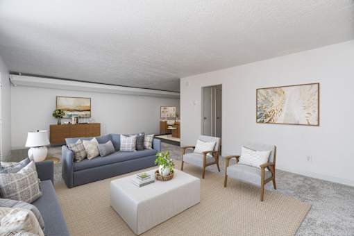 A living room with a grey couch, a white coffee table, and a painting on the wall.