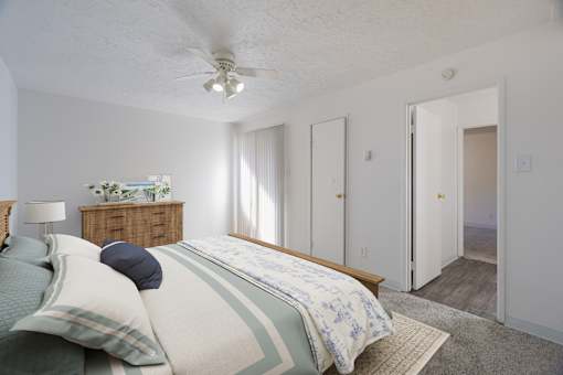 A bedroom with a bed, nightstand, and a ceiling fan.