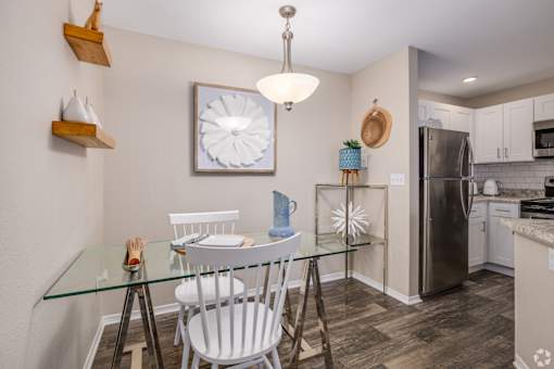 Dining area with glass table and kitchen at Fusion Apartments, Florida
