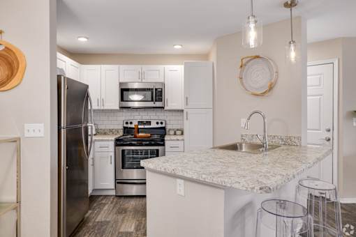 Kitchen with white cabinets and granite peninsula at Fusion Apartments, Florida, 32818
