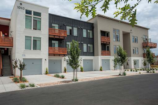 A row of modern townhouses with garages and trees in front.