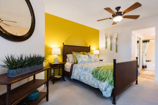 a bedroom with a yellow accent wall and a ceiling fan