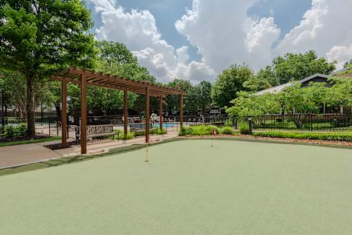 A green pool surrounded by trees and a wooden pergola.