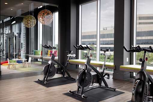 A gym with stationary bikes and a view of the outside.