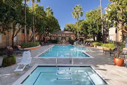 A pool surrounded by trees and chairs.