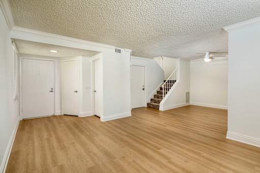 A spacious living room with wooden floors and white walls.