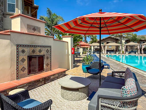 A patio with a red umbrella and blue chairs.