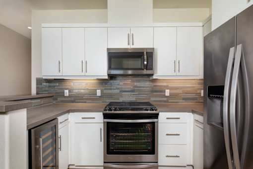 A modern kitchen with white cabinets and a stainless steel refrigerator.