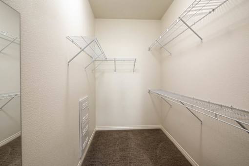 A walk-in closet with shelving and a mirror.