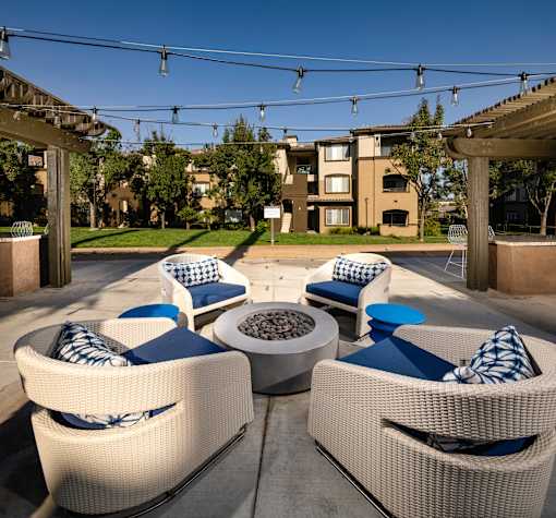 A patio with white wicker chairs and blue cushions.