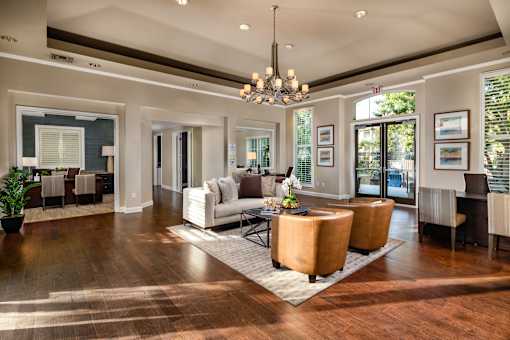 A large, well-lit living room with a wooden floor and a variety of seating options.