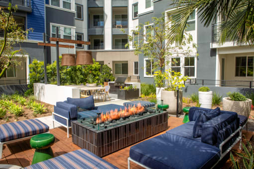 a patio with blue couches and a fire pit in front of an apartment building at Citron, Anaheim, CA