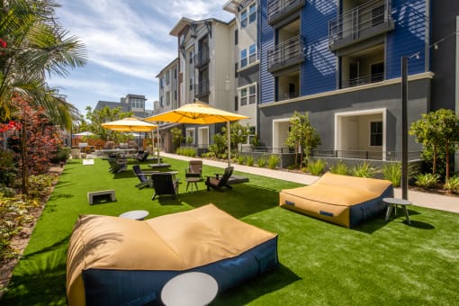 a grassy area with couches and umbrellas in front of an apartment building at Citron, Anaheim, California