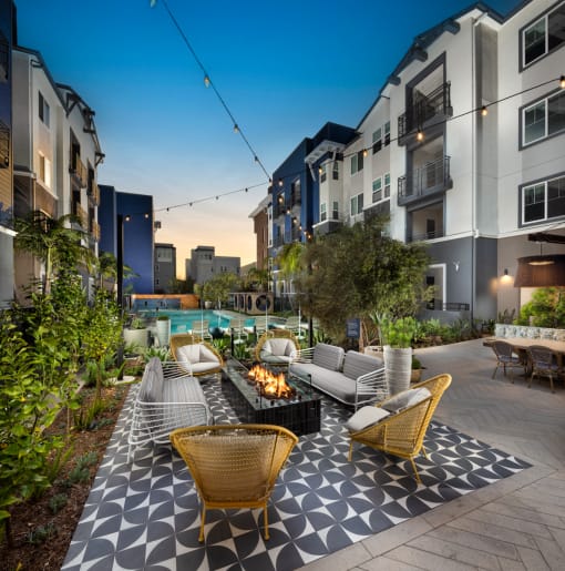 an outdoor lounge area with lounge chairs and a fire pit in front of an apartment building at Citron, Anaheim, 92805